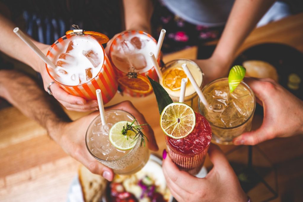 Group of excited friends enjoying happy hour cocktails served at Perch + Plow