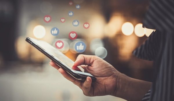person's hand using cell phone to post to social media