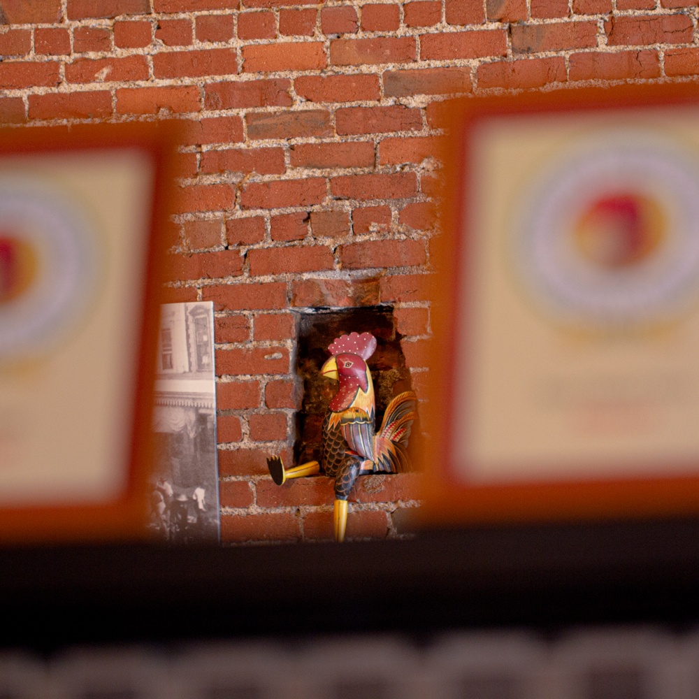 Rooster knick-knack displayed in nook of brick wall at Seared Petaluma