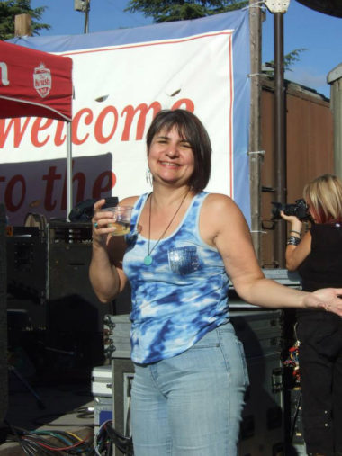 smiling woman holding wine in plastic cup at outdoor music event