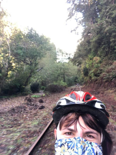 woman with mask and helmet riding a railbike through the woods