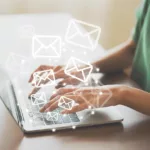 woman's hands typing on laptop with envelope graphics flying into the air