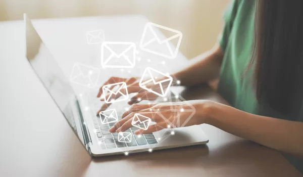 woman's hands typing on laptop with envelope graphics flying into the air